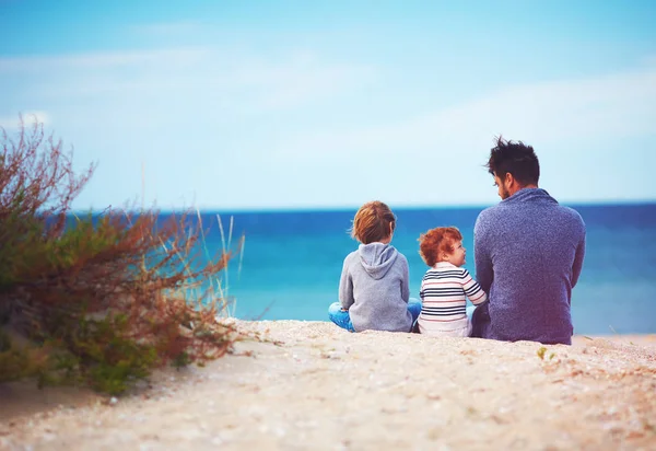 Padre e hijos en la playa de arena cerca del mar en el día ventoso — Foto de Stock