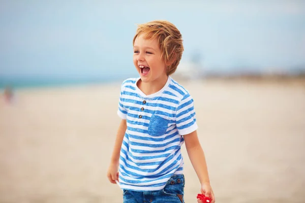 Young delighted boy, kid playing with a toy propeller, having fun on summer beach — Stock Photo, Image