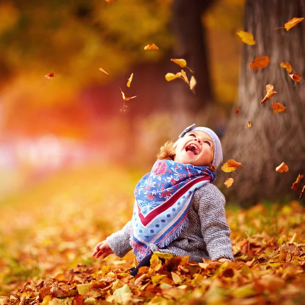 Восхитительная счастливая девочка, ловящая опавшие листья, играя в — стоковое фото