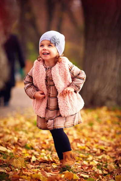 Linda niña de moda caminando en el parque de otoño entre hojas caídas —  Fotos de Stock
