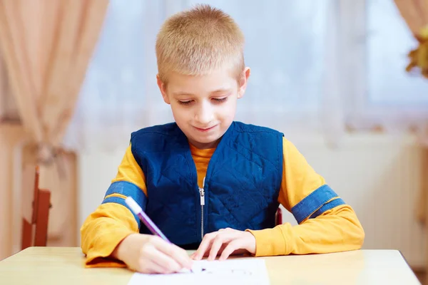 Cute kid with special need sitting at the desk , writing in notebook in classroom — Stock Photo, Image
