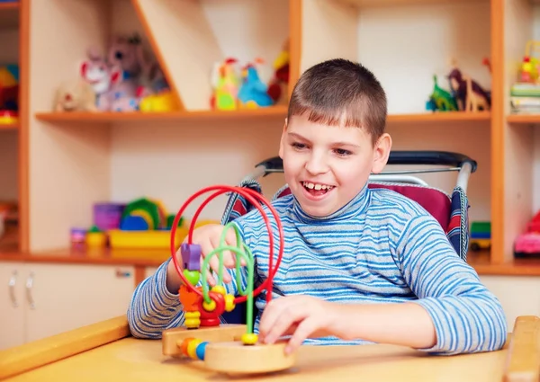 Веселий хлопчик з інвалідністю в реабілітаційному центрі для дітей з особливими потребами, вирішення логічної головоломки — стокове фото