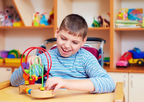 論理パズルを解く、特別なニーズを持つ子供のためのリハビリテーション センターで障害を持つ陽気な少年 — ストック写真