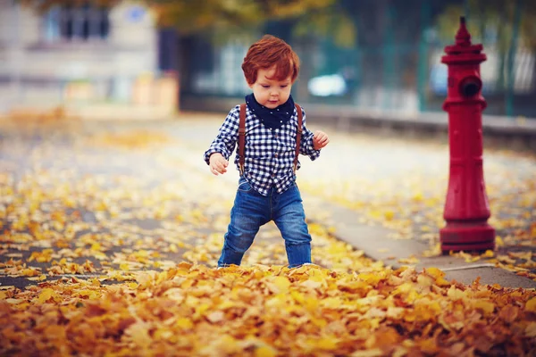 Симпатичный рыжеволосый мальчик, идущий по осенней улице — стоковое фото