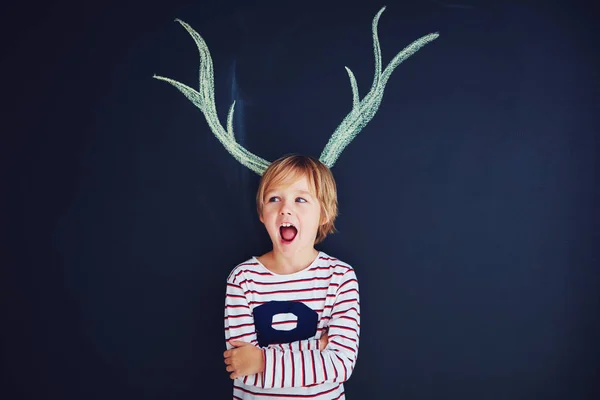 Niño divertido, niño con cuernos dibujados de pie delante de una pared de tiza —  Fotos de Stock