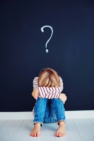 Triste, frustrado chico de escuela sentado en el suelo con signo de interrogación por encima de él — Foto de Stock