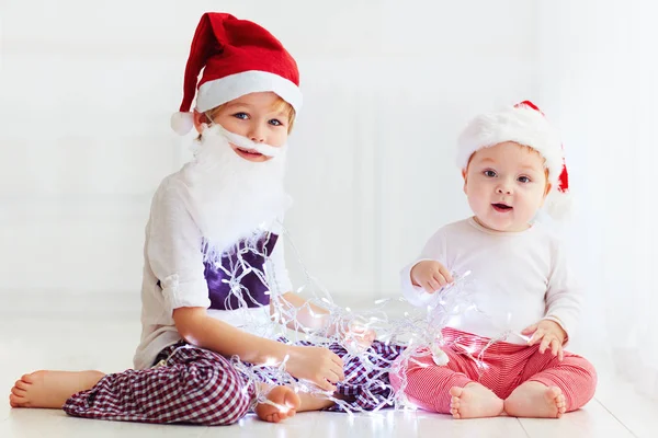 Cute brother siblings, kids in santa's hats and garland playing at home — Stock Photo, Image