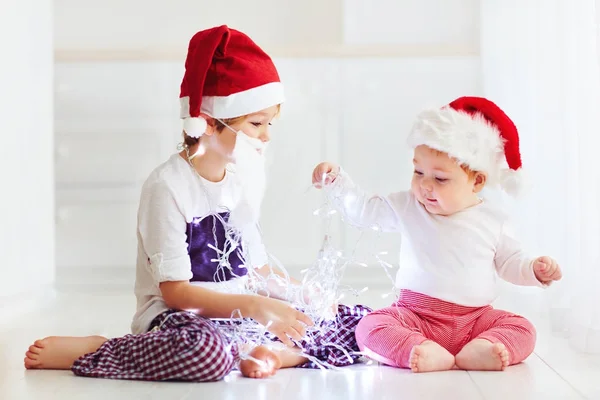 Schattig broer broers en zussen, kinderen in santa's hoeden en garland spelen thuis — Stockfoto