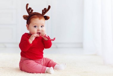 sevimli küçük Kızıl saçlı bebek çocuk Noel tatlı tatma Ren geyiği grubu ile davranır, yere evde oturmak