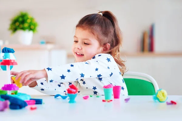 Linda niña jugando con arcilla de modelado colorido —  Fotos de Stock