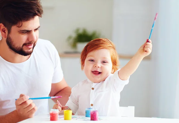 Gelukkig weinig baby kunstenaar tekenen met kleurrijke verf en vader thuis — Stockfoto