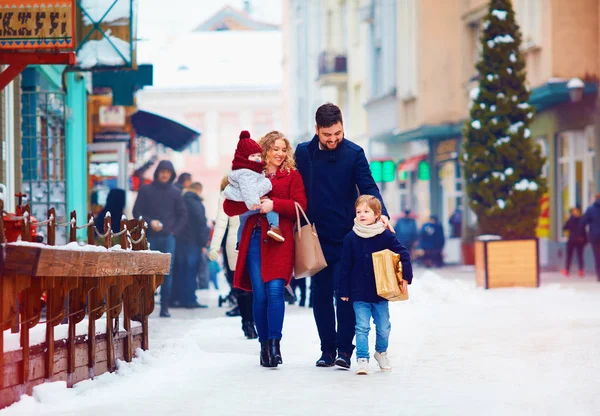 Família feliz andando juntos na rua da cidade nevada durante o inverno — Fotografia de Stock