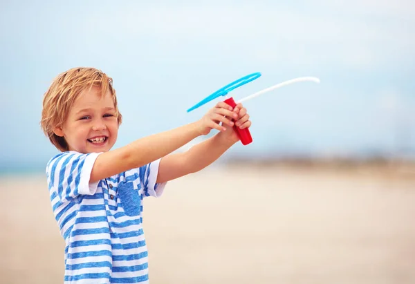 喜んでいるかわいい少年、砂浜のビーチで楽しい時を過す子供レジャー活動とゲーム プロペラ グッズ — ストック写真