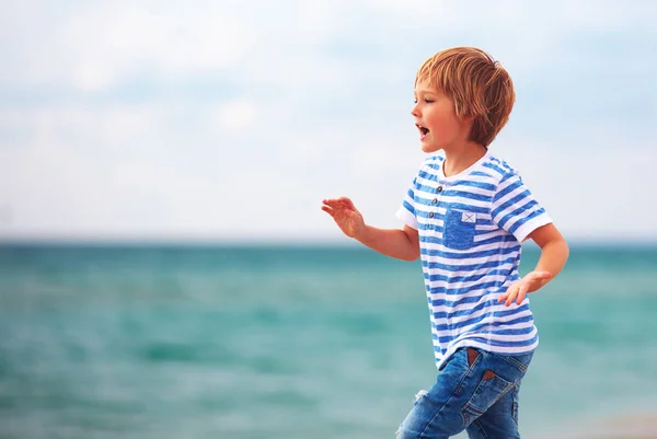Милый мальчик, бегущий вдоль моря, летний пляж — стоковое фото