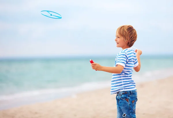 Blij schattige jonge jongen, kind plezier op zandstrand, recreatieve activiteit spelen met speelgoed van de propeller — Stockfoto