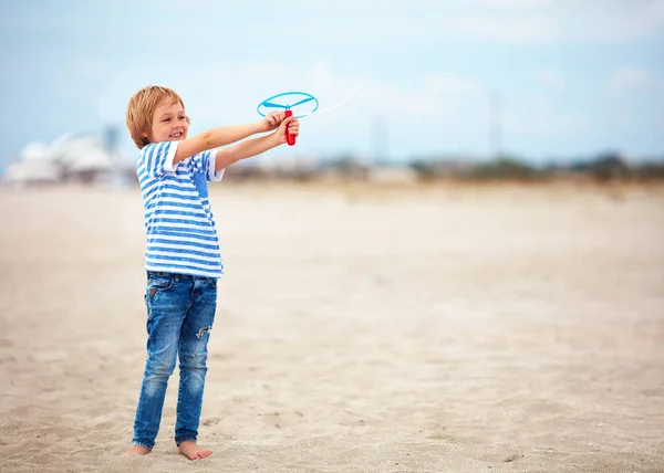 Encantado bonito menino, criança se divertindo na praia de areia, jogando jogos de atividade de lazer com brinquedo de hélice — Fotografia de Stock