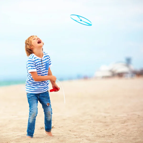 Encantado lindo niño, niño que se divierte en la playa de arena, jugando juegos de ocio con el juguete de la hélice — Foto de Stock