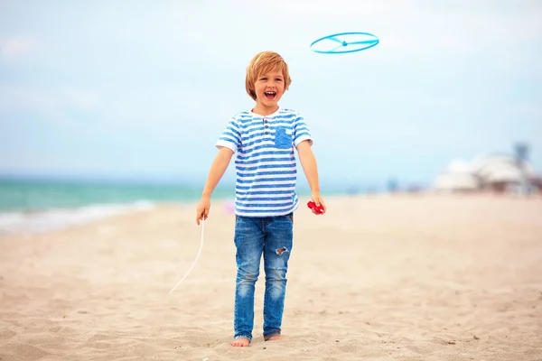 Blij schattige jonge jongen, kind plezier op zandstrand, recreatieve activiteit spelen met speelgoed van de propeller — Stockfoto