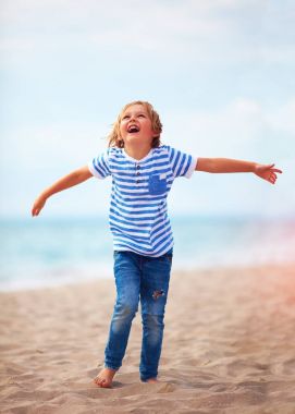 güzel bir duygusal çocuk, mutluluk, kumlu plaja çalışan ile parlayan çocuk