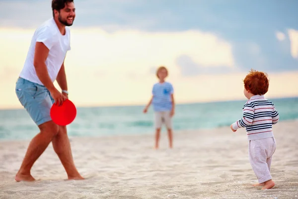 Glücklicher Vater mit Kindern, Familie spielt fliegendes Discgolf am Abendstrand — Stockfoto