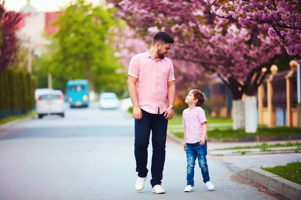 かわいい陽気な父と息子のばねの通りに沿って歩く — ストック写真