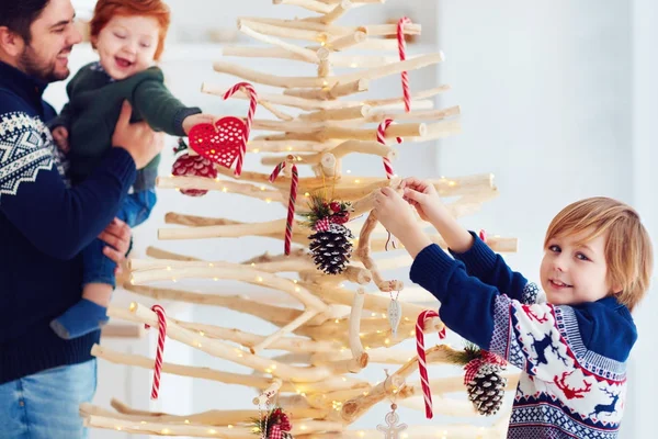 Familjen dekorerar en extraordinär julgran gjord av grenar och drivved hemma — Stockfoto
