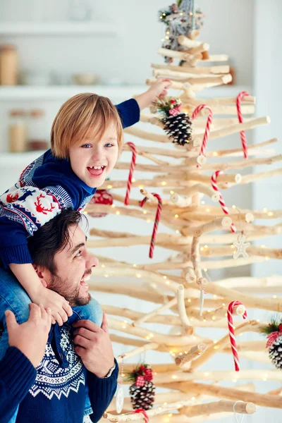 Lycklig far och son dekorera miljövänlig julgran gjord av grenar som var avskurna under sanitära arbete — Stockfoto