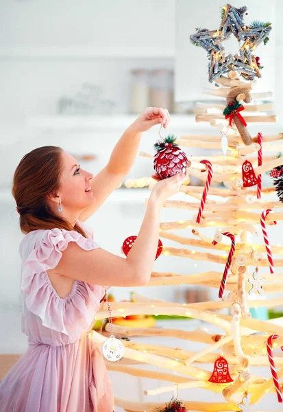 young woman decoration extraordinary, eco friendly christmas tree made of branches, winter holidays