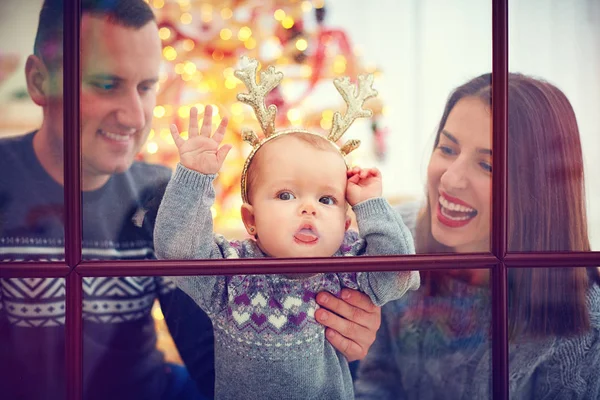Söt baby tjej slickar fönstret njuter av julen med familjen hemma — Stockfoto