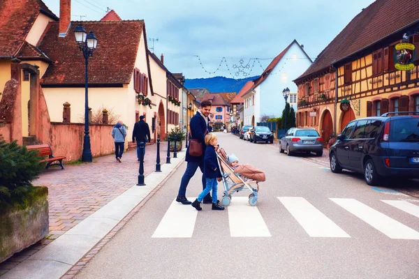 Eguisheim, Elsass, Frankreich - 24. Dezember 2017: niedliche Familie überquert die Straße eines mittelalterlichen Dorfes — Stockfoto