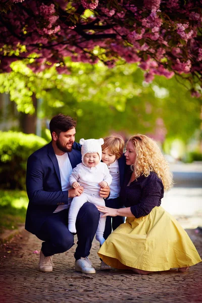 Porträtt av lycklig familj på promenad längs gatan blommande våren — Stockfoto