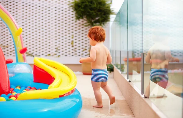 Pelirroja bebé chico tener divertido corriendo alrededor inflable niño piscina a — Foto de Stock