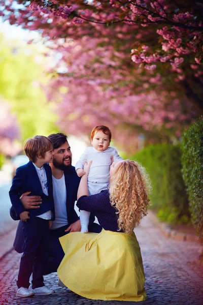 Porträtt av lycklig familj på promenad längs gatan blommande våren — Stockfoto