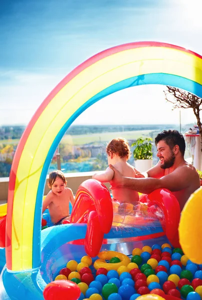 Familia divertirse en la piscina inlatable con tobogán y un montón de bolas de colores —  Fotos de Stock
