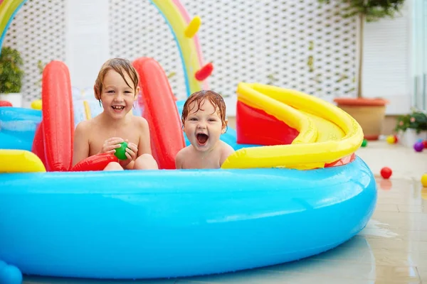 Niños emocionados, familia que se divierte en la piscina inflable colorida en el patio —  Fotos de Stock
