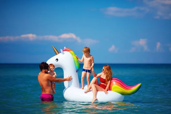 Glückliche Familie genießt Sommerurlaub, Spaß im Wasser auf aufblasbarem Einhorn — Stockfoto