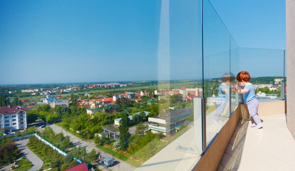 малыш наслаждается видом на город с террасы на крыше в многоэтажном здании
