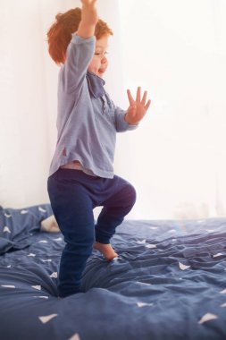 eğleniyor, yatağa atlama şirin küçük yürümeye başlayan çocuk bebek