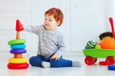 Mutlu bebek çocuk piramidin üzerinde renkli halkalar sıralıyor.