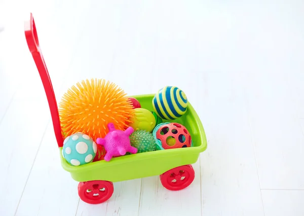 Colorido carro de juguete lleno de diferentes bolas táctiles de color y forma para el desarrollo infantil —  Fotos de Stock