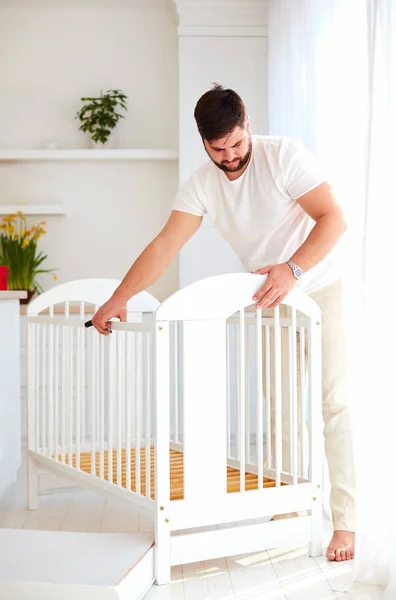 Otec, instalace postýlce, příprava na narození dítěte v rodině — Stock fotografie