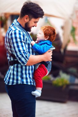 mutlu baba ile bebek şehirde yürüyüşe sahip sling sırt çantası içinde