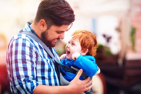 Felice padre e figlio bambino in fionda zaino avendo una passeggiata in città — Foto Stock