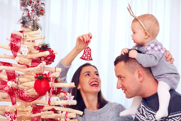 Feliz joven familia decorar decorar eco árbol de Navidad en casa —  Fotos de Stock