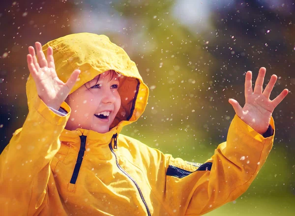 happy kid catching rain drops in spring garden