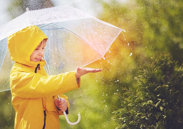 Happy kid catching rain drops in spring park — Stock Photo, Image