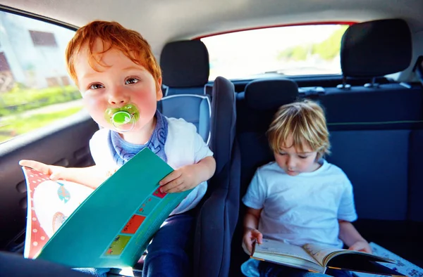 Crianças sentadas no banco de trás, lendo livro enquanto viajam no carro — Fotografia de Stock