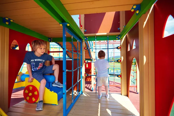 Счастливые дети играют в игры на красочной детской площадке замка — стоковое фото