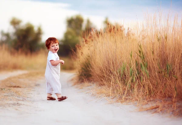 Lindo pelirroja bebé niño caminando a lo largo del camino de verano — Foto de Stock