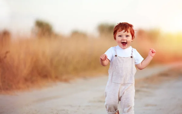 Очаровательный рыжий мальчик бежит по летнему пути — стоковое фото